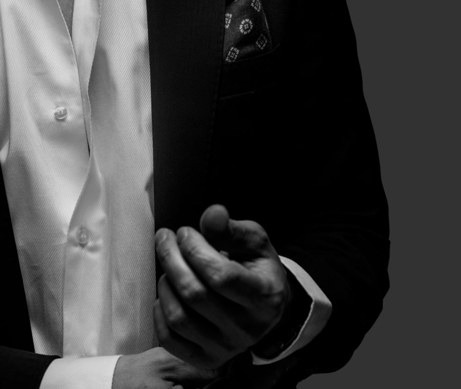 Part of  black and white portrait of male in a suit on dark grey background.