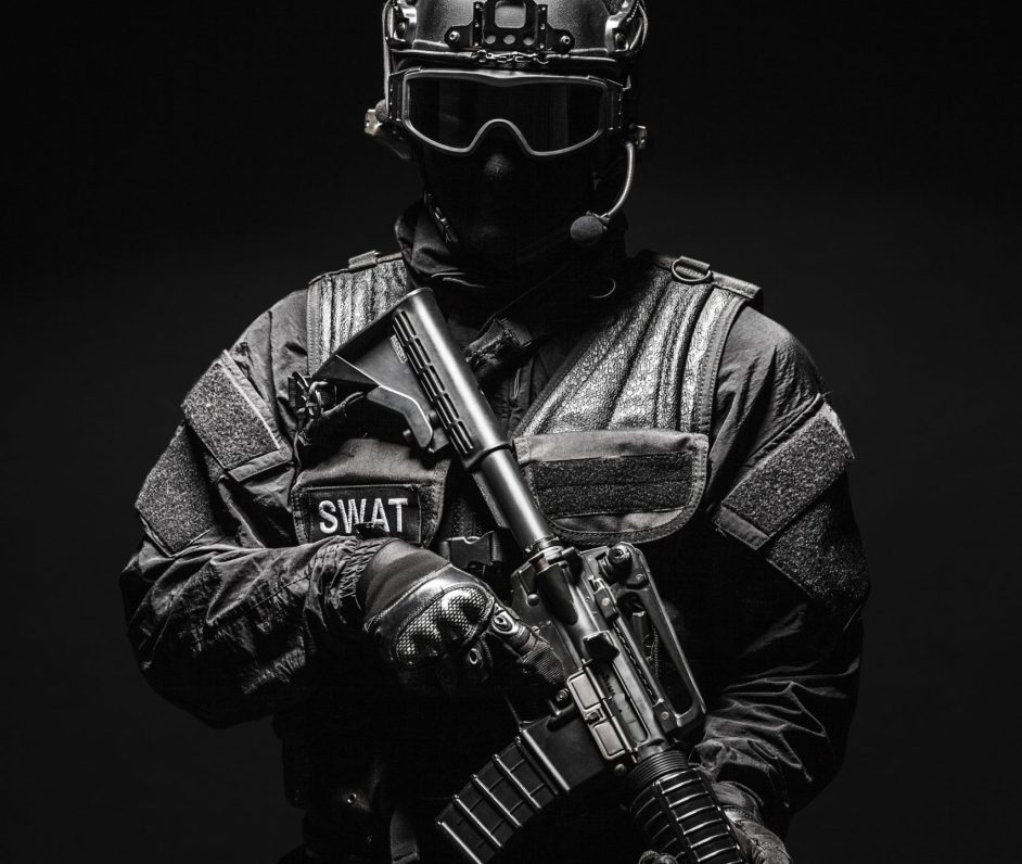 Spec ops police officer SWAT in black uniform and face mask studio shot