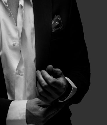 Part of  black and white portrait of male in a suit on dark grey background.